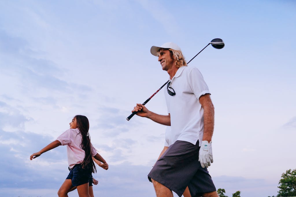 A Man Holding a Golf Club while Walking with a beginner golfer 