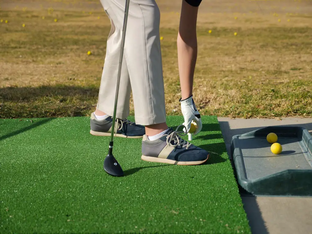 Person wearing golf shoes hold golf club Putting a Ball on a Tee